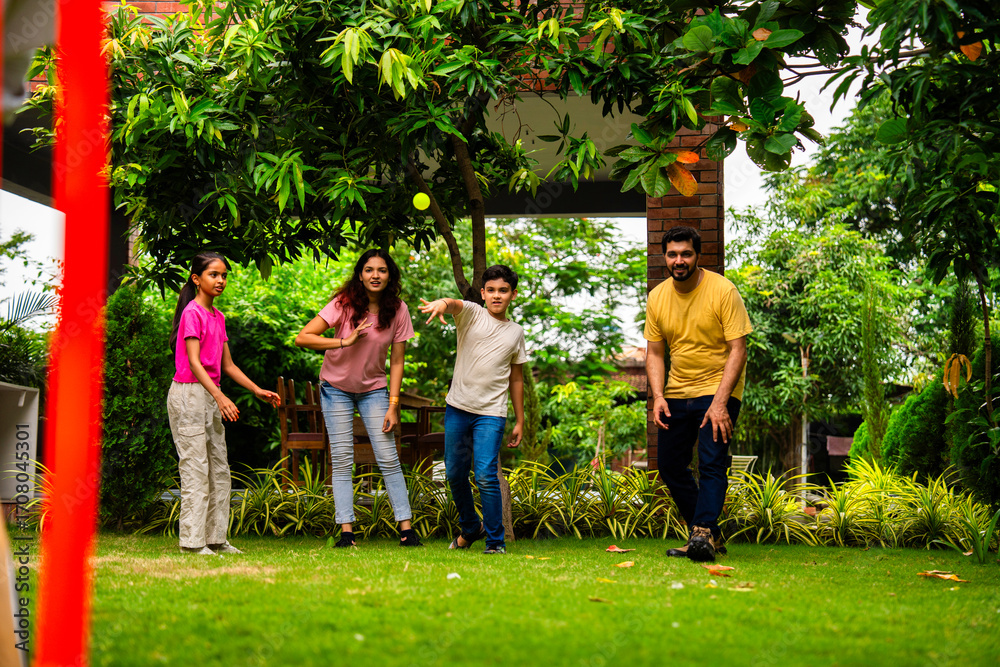 Fototapeta premium Indian family plays cricket bowling at home, enjoying weekend fun with kids in garden