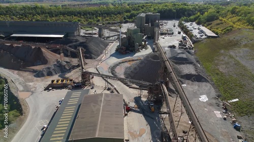 Aerial drone view of huge quarry mining operational facility, extracting rare earth minerals, heavy plant machinery and industrial conveyor belts in Coalville England UK sunny 