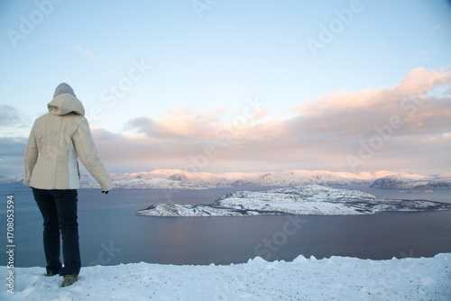 Donna con vestiti invernali sul punto panoramico nell'Artico a nord della Norvegia. Belvedere a Sørstraumen, isole di Spildra e Skorpa. Fiordo Kvaenangen.