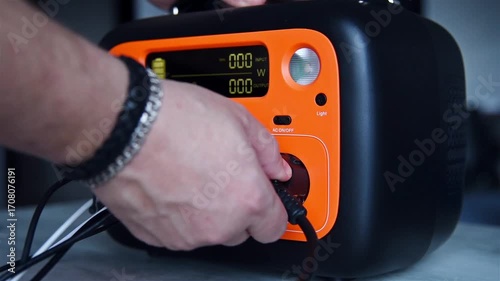 Man's hand connects charging cable to charging station. Concept of energy conservation. Slow Motion Effect.