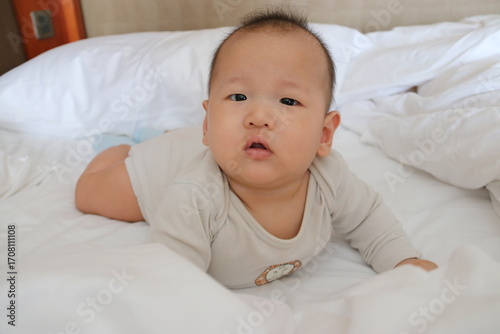 Adorable baby doing tummy time on the bed
