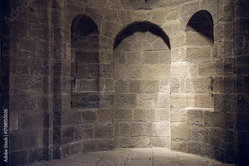Historic stone room with multiple arches and sunlight creating dramatic shadows
