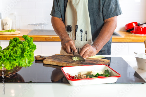 Man Cooking in Kitchen Cutting Vegetables on Wooden Board
