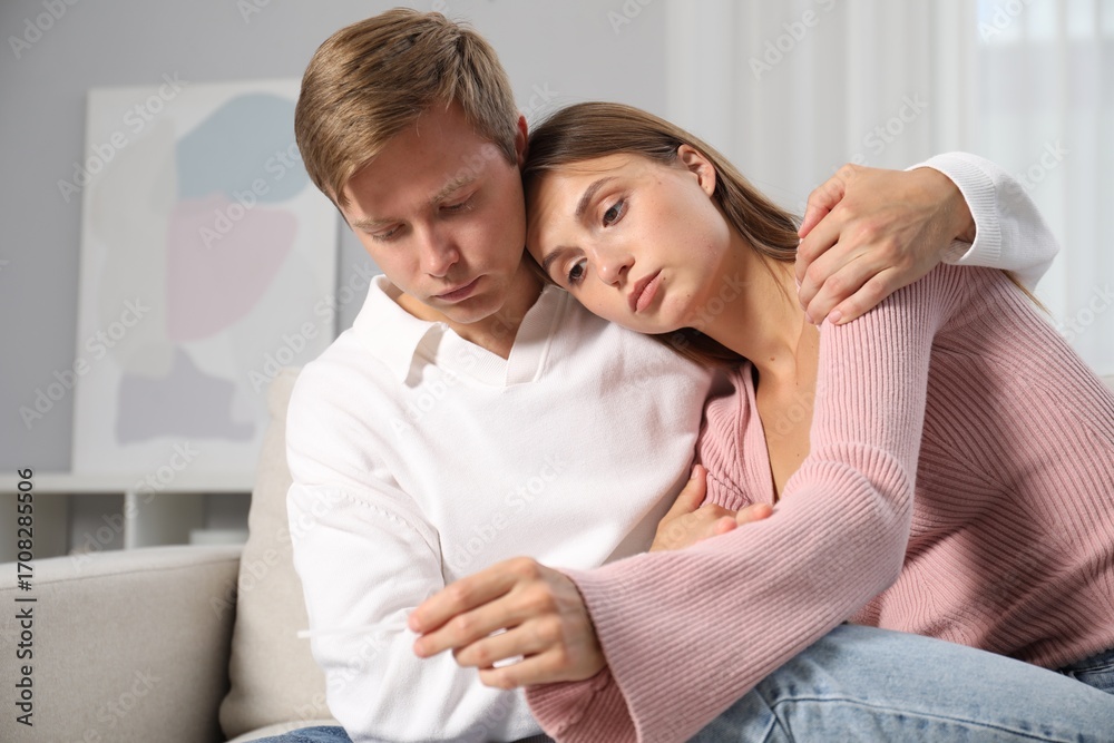 Worried couple with pregnancy test on sofa at home Worried couple with pregnancy test on sofa at home