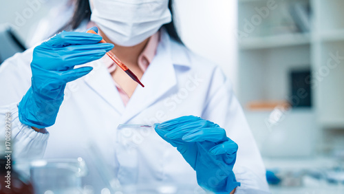 Female scientist in protective gear handling a blood sample in a laboratory, representing virus testing, COVID-19 diagnostics, medical research, healthcare innovation, and scientific precision.