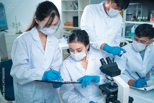 Bilde på lerret Group of scientists collaborating in a laboratory, engaging in teamwork and planning around experiments, symbolizing cooperation, diversity, and innovation in healthcare and science