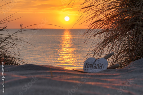 Sonnenuntergangsstimmung in den Dünen von Zeeland mit einen weißen Herz im Meeressand der Dünen mit der Aufschrift Zeeland.