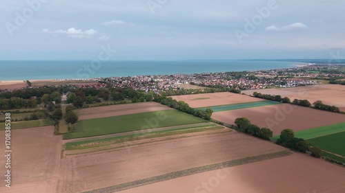 Aerial view of serene coastal farmland and quaint village by the sea.