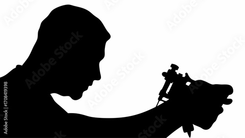 Silhouette of a man holding a tattoo machine in his hand ready to create artwork on someone's skin