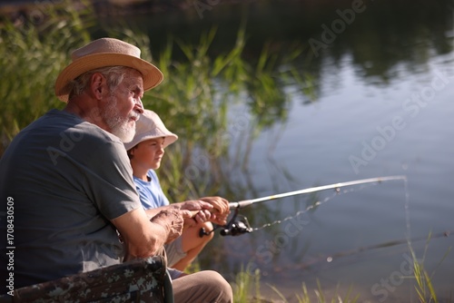 Fotografía Grandfather and his nephew fishing together near river outdoors