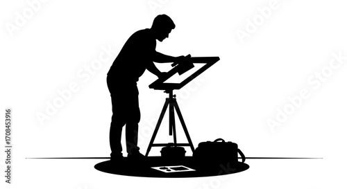 Artist silhouette meticulously working on a drawing easel with creative tools and bag nearby