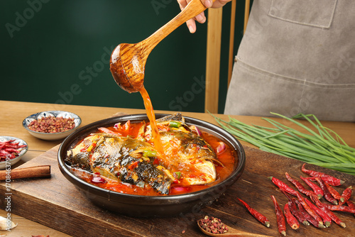 Traditional Fish Head Stew with Wooden Ladle Pouring Sauce in Clay Pot Asian Cuisine