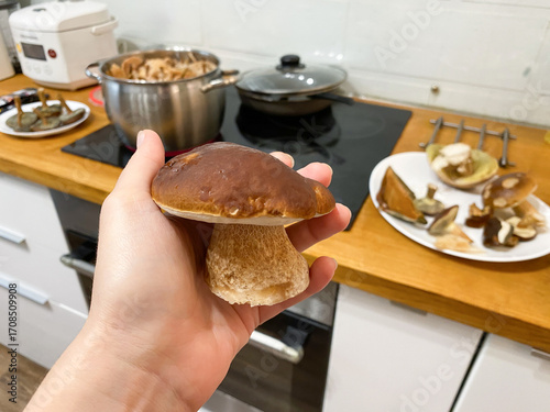 A man prepares mushrooms in the kitchen. He holds a mushroom in his hand against the background of the kitchen.