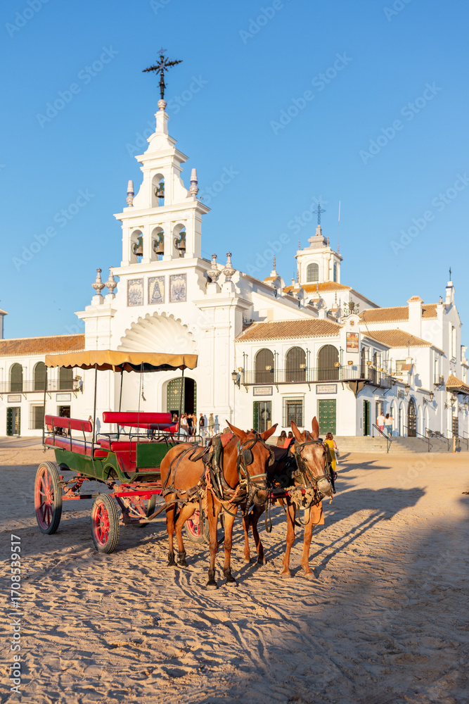Obraz premium El Rocio, Sevilla, Andalusia, Spain. 28 August 2025. Horses with a cart in front of the Hermitage of El Rocio