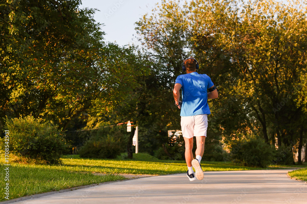 Fototapeta premium Man running in park on sunny day, low angle view