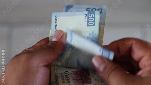 Close-up of hands counting a stack of mexican 500 and 1000 pesos bills