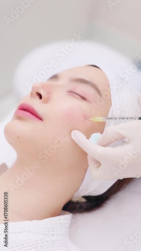 A close-up of a young Asian woman receiving a Botox or dermal filler injection in her face from a professional. Concept for beauty clinics, dermatology, and anti-aging treatments.