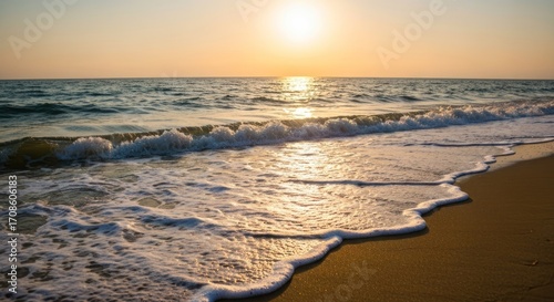 Golden sunset over a beach. Waves gently lap the shore
