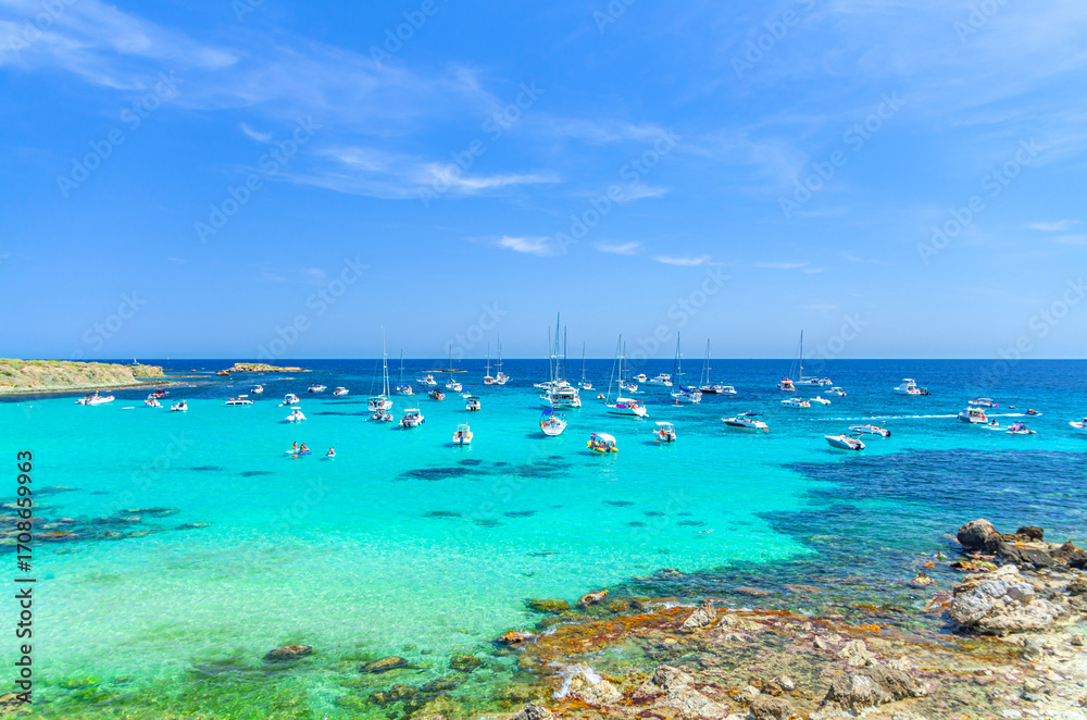 Fototapeta premium Yachts and motor boats anchored in azure turquoise water of lagoon Alicante bay Mediterranean Sea near coast Tabarca Island Nueva Tabarca Isla Plana in sunny summer day, Valencian Community, Spain