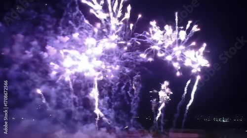 Violet fireworks explode in a dazzling display against a dark night sky