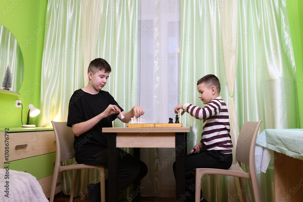 Fototapeta premium Boy in red hoodie lies on sofa using tablet, enjoying free time in the room.