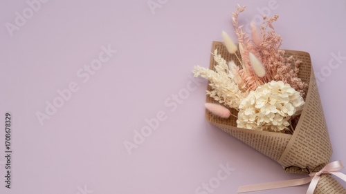Floral Elegance: A delicate arrangement of dried flowers, delicately wrapped in rustic burlap, rests against a gentle, monochromatic pastel backdrop.
