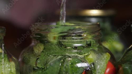 Home preservation. Assorted tomatoes with cucumbers in glass jars are poured with boiling water.