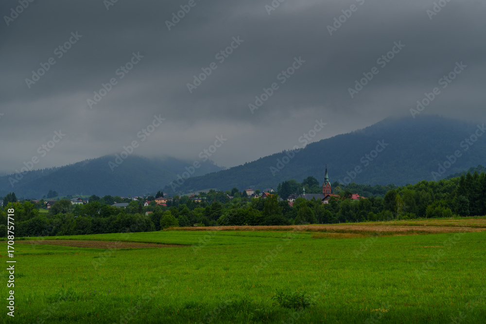 Obraz premium Dark Clouds over Meadow with Distant Church