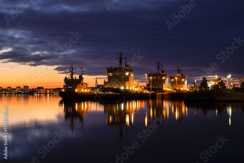 Dramatic sunset over Luleå city and the icebreaker boats on an autumn evening. In the background, the landmarks of the cityscape rise