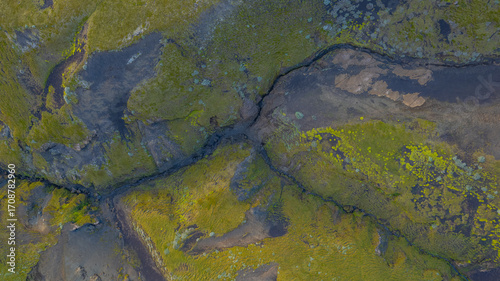 Top down aerial of green moss wetlands in Iceland with dark volcanic soil and small rivers creating abstract natural textures in landscape