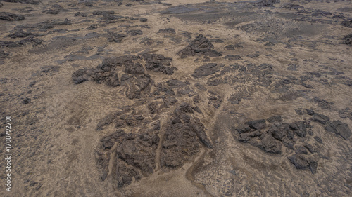 Aerial view of barren rocky terrain in Iceland with scattered dark stone formations on sandy ground showing raw untouched natural scenery