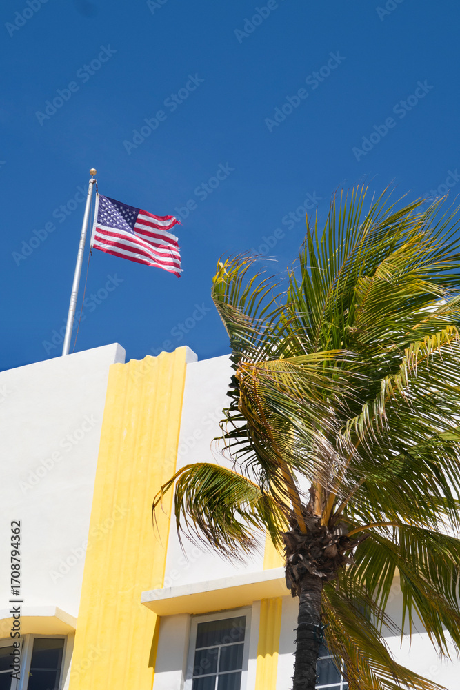 White and yellow building detail, palm tree and american flag