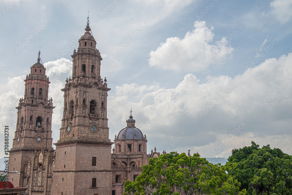 Obraz premium Streets, landscapes, and architecture of Morelia, Michoacan, Mexico, Pink quarry towers of the cathedral in the historic center with a blue sky with clouds. Horizontal or panoramic view