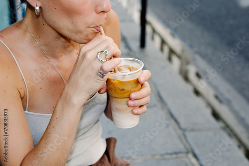 Female tourist enjoying an iced coffee outside a rustic café in Paris