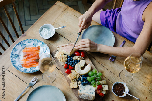 Unknown woman preparing a platter of French cheeses to enjoy with wine