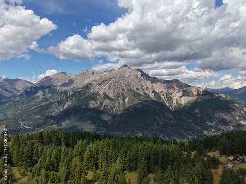 High mountain landscape in the French Alps, forest and rocky peaks near Briançon – Aerial view with chalets