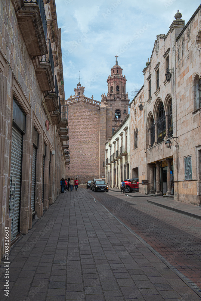 Obraz premium Streets, landscapes, and architecture of Morelia, Michoacan, Mexico, Pink quarry towers of the cathedral in the historic center with a blue sky with clouds. back street