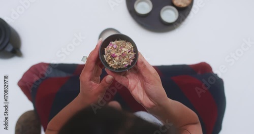 Overhead view of woman smelling tea leaves from bowl