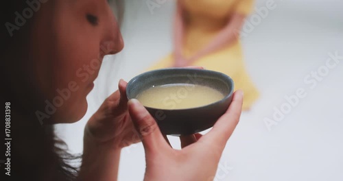 Overhead side profile of woman drinking tea with friends in background