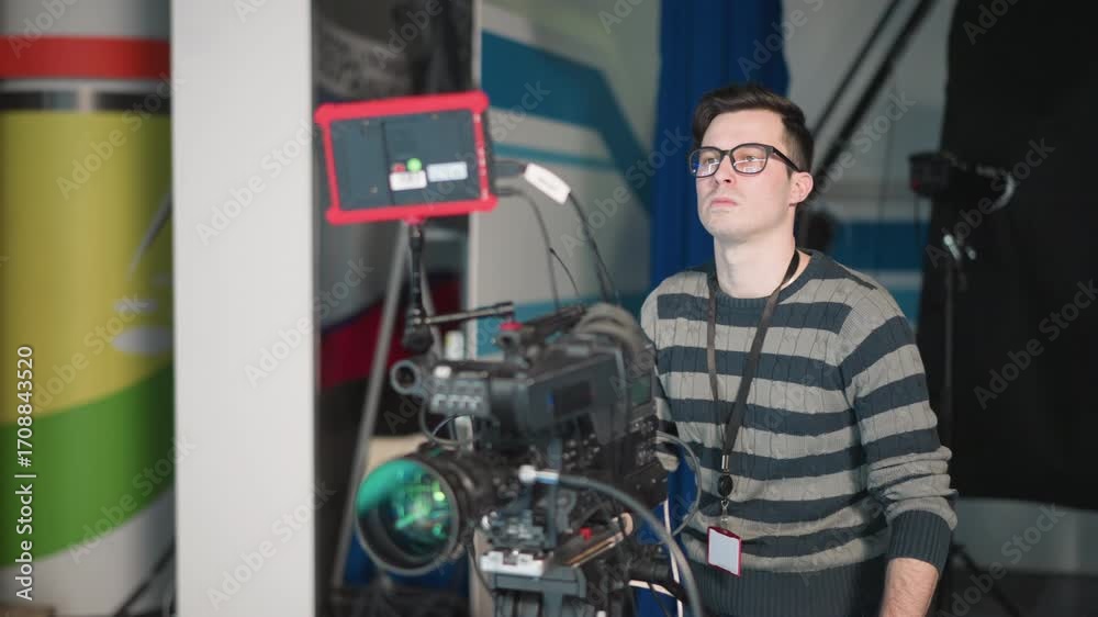 Camera operator focused on adjusting broadcast camera settings ...
