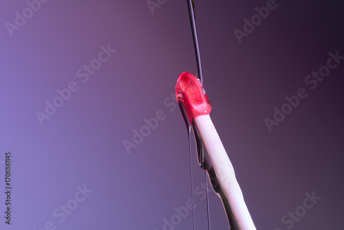 Purple lip gloss brush close up with a liquid flowing down