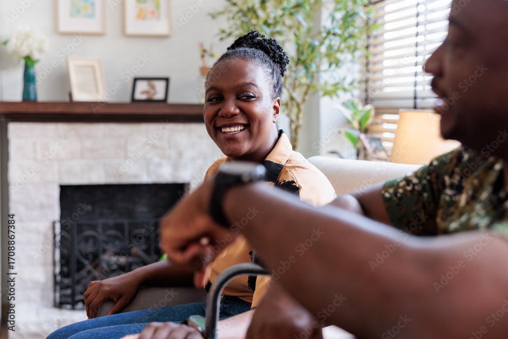 © Jovo Jovanovic/Stocksy - Couple conversing in a living room, one smiling. © Jovo Jovanovic/Stocksy - Couple conversing in a living room, one smiling.