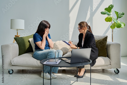 Sad unhappy woman in therapy session with female psychologist
