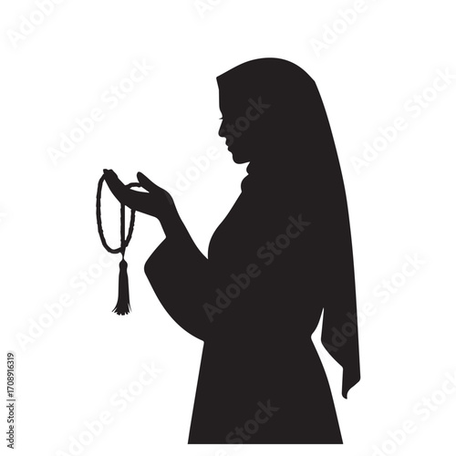 Silhouette of a muslim woman wearing a hijab holding prayer beads in her hand in profile view