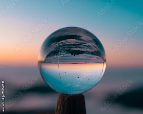 Crystal ball reflecting a beautiful sunset over a sea of clouds landscape