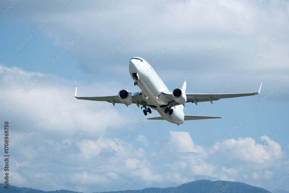 Fototapeta premium White plane climbing higher against the clouds. Airplane flying in the blue sky, take-off from airport