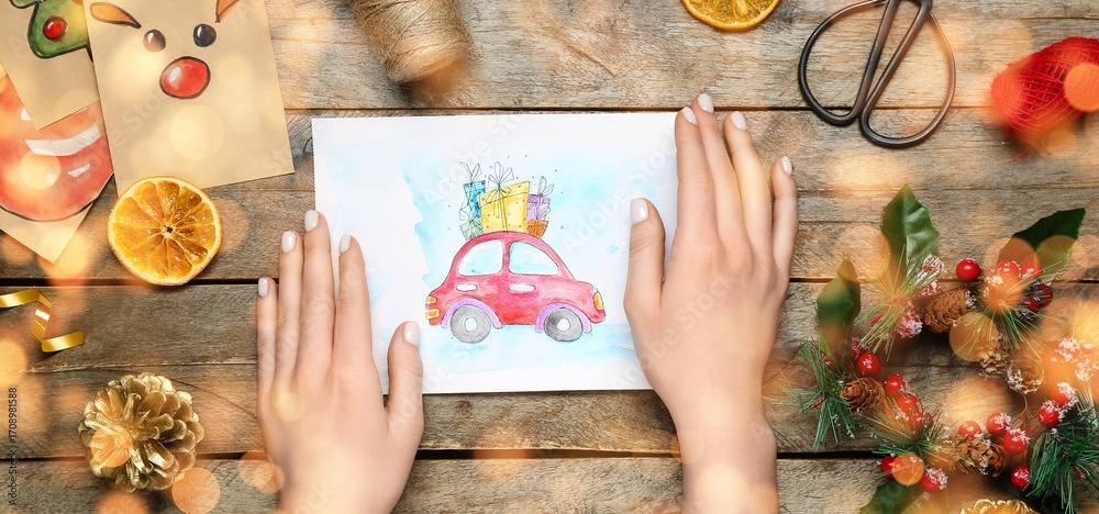Naklejka premium Female hands with beautiful Christmas card and decor on wooden background, closeup