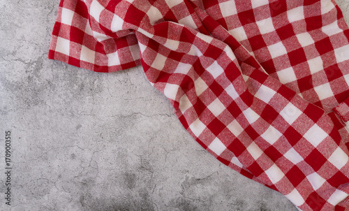 Top view of a red and white checked tablecloth in a corner of a gray surface