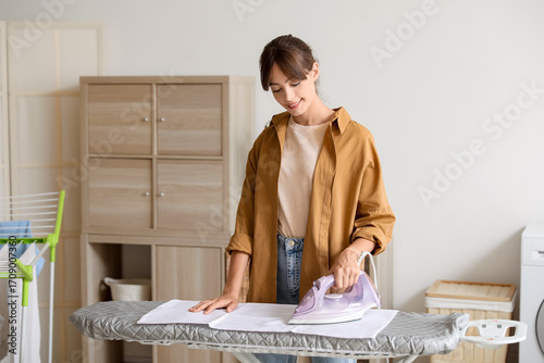 Young woman ironing clean l...