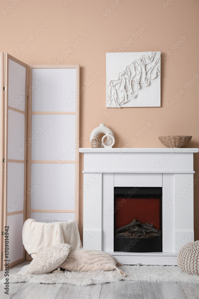 Fototapeta premium Fireplace, pillows and folding screen in interior of light living room